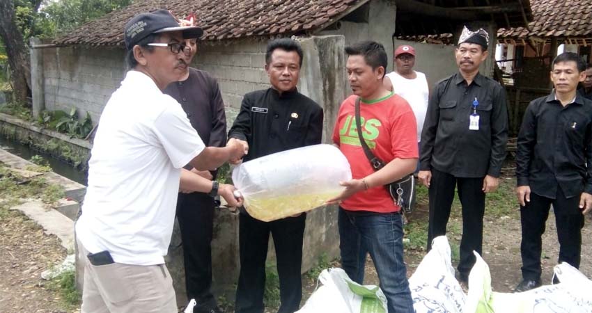 Ketua Karang Taruna PRIMA, Indra Guna Purwadi ketika menerima bantuan bibit ikan dari BNI Genteng, Hariyono disaksikan Camat Genteng Firman Sanyoto dan Kepala Desa Kembiritan Sukamto. (tut)